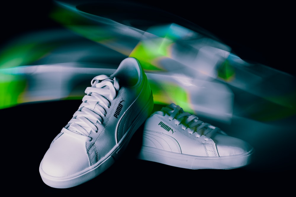 a pair of white and green sneakers on a black background