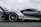 A sleek, high-performance sports car moving at speed. The car has a modern aerodynamic design with a prominent rear spoiler and a predominantly metallic color scheme. The blurred background suggests motion, highlighting the car's dynamic presence on what appears to be a racetrack.