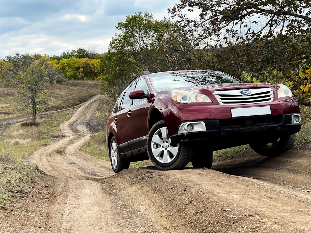 a red car driving down a dirt road