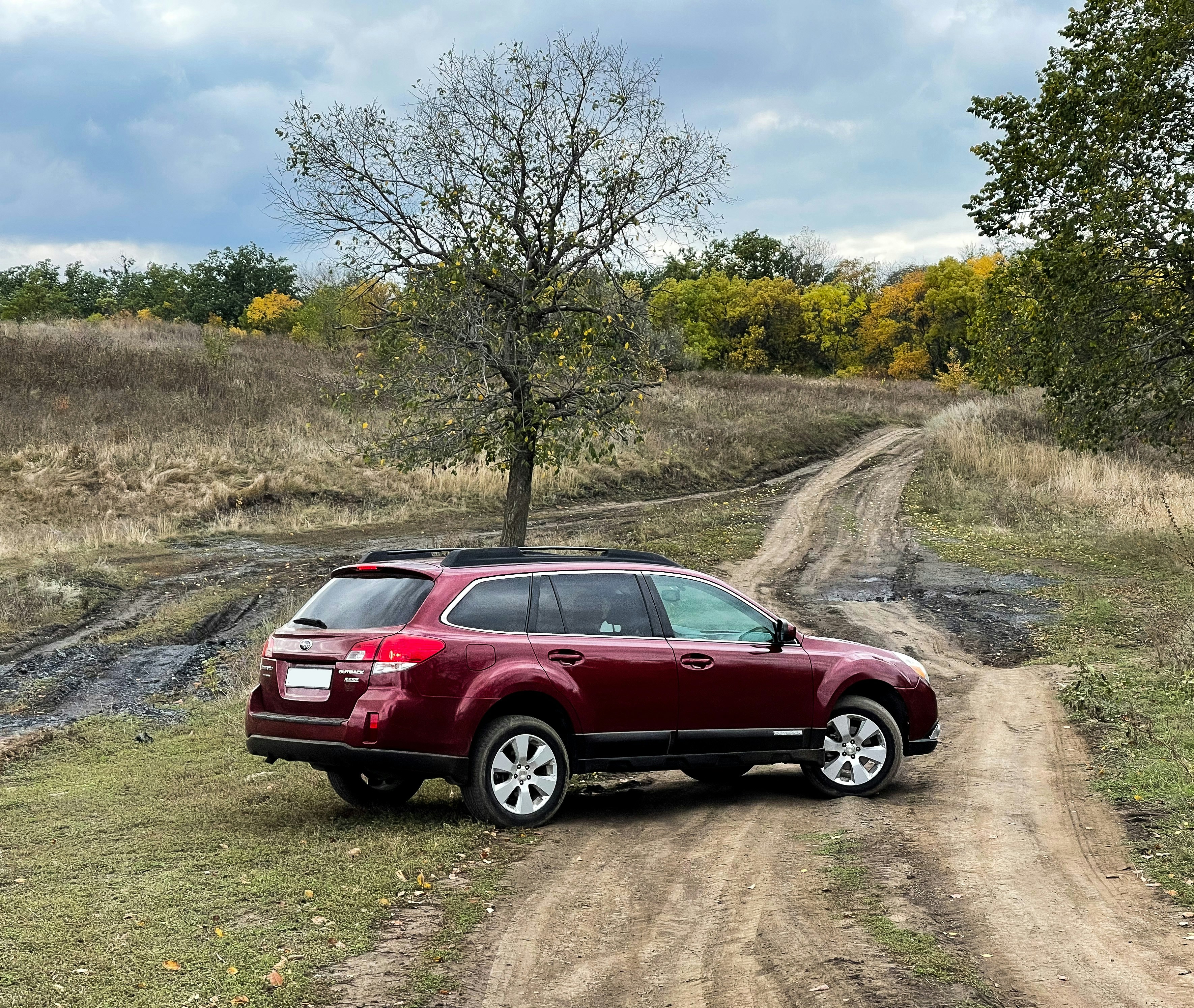 a red suv is parked on a dirt road