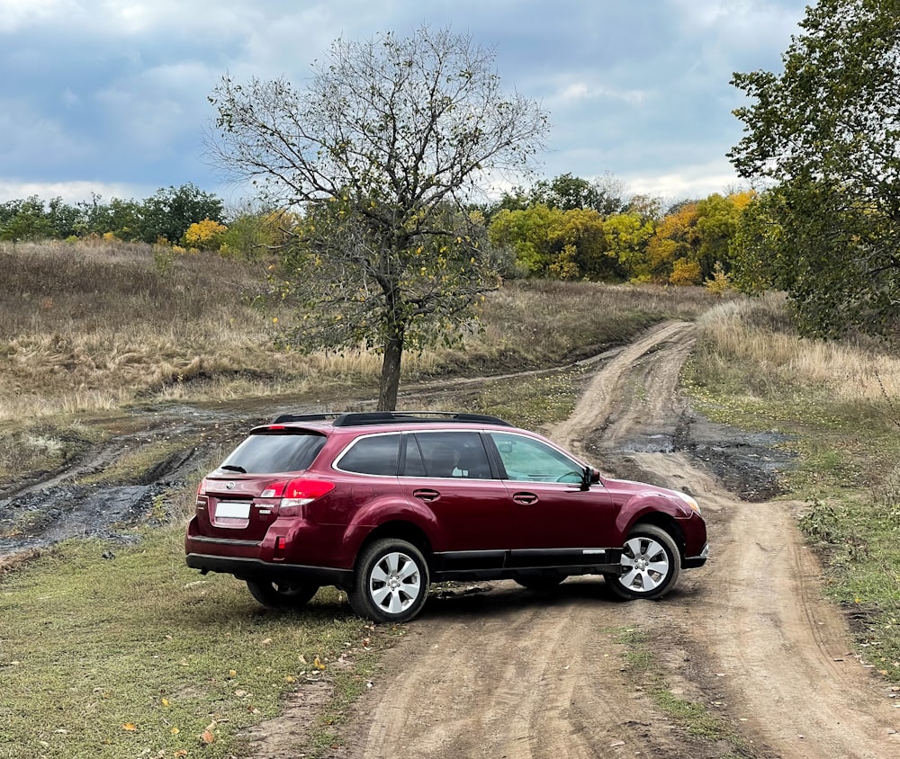 a red suv is parked on a dirt road