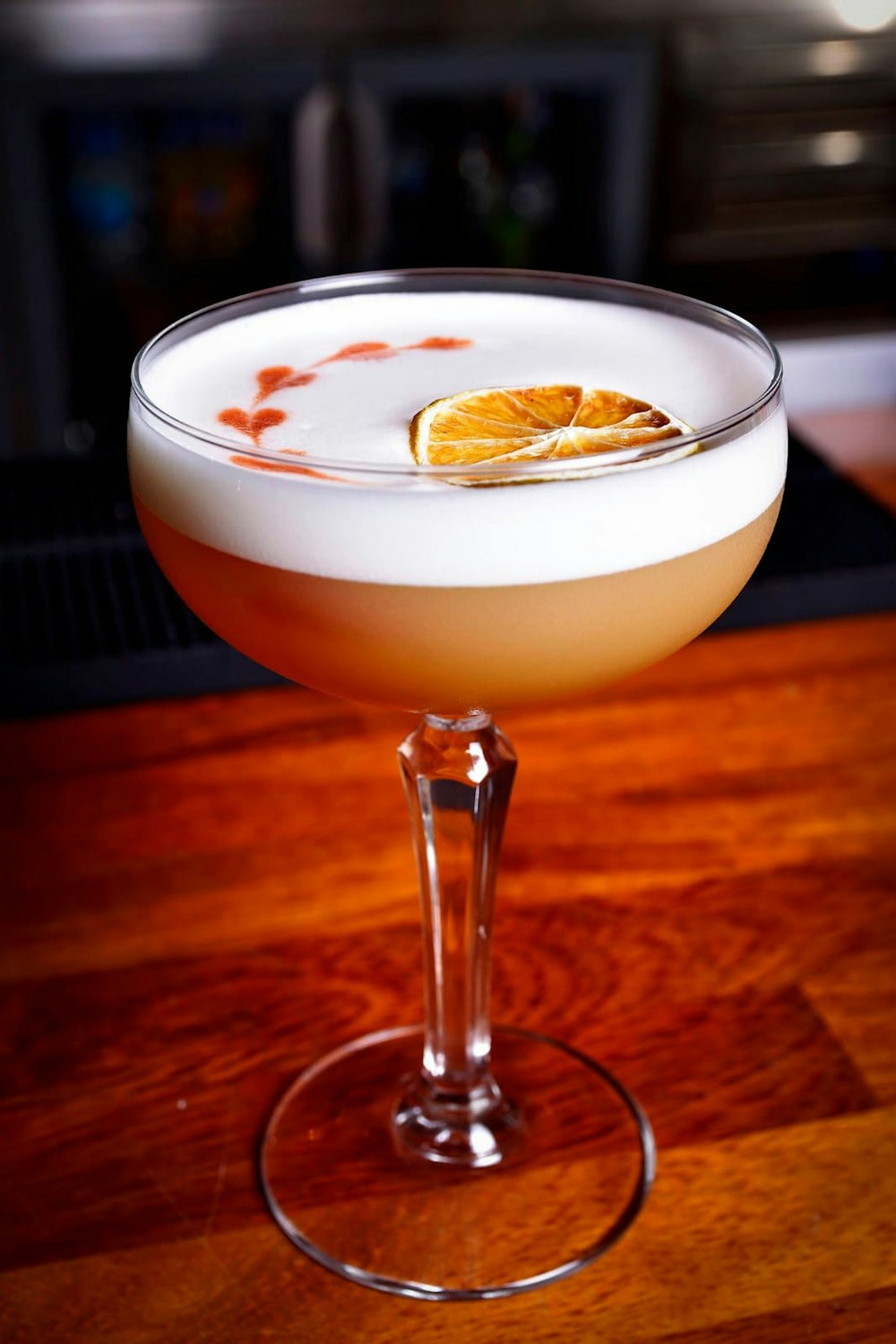 a glass filled with a drink sitting on top of a wooden table