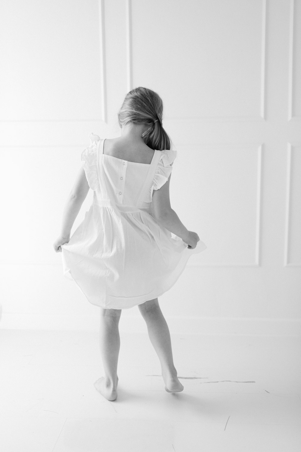 a little girl in a white dress standing in a room