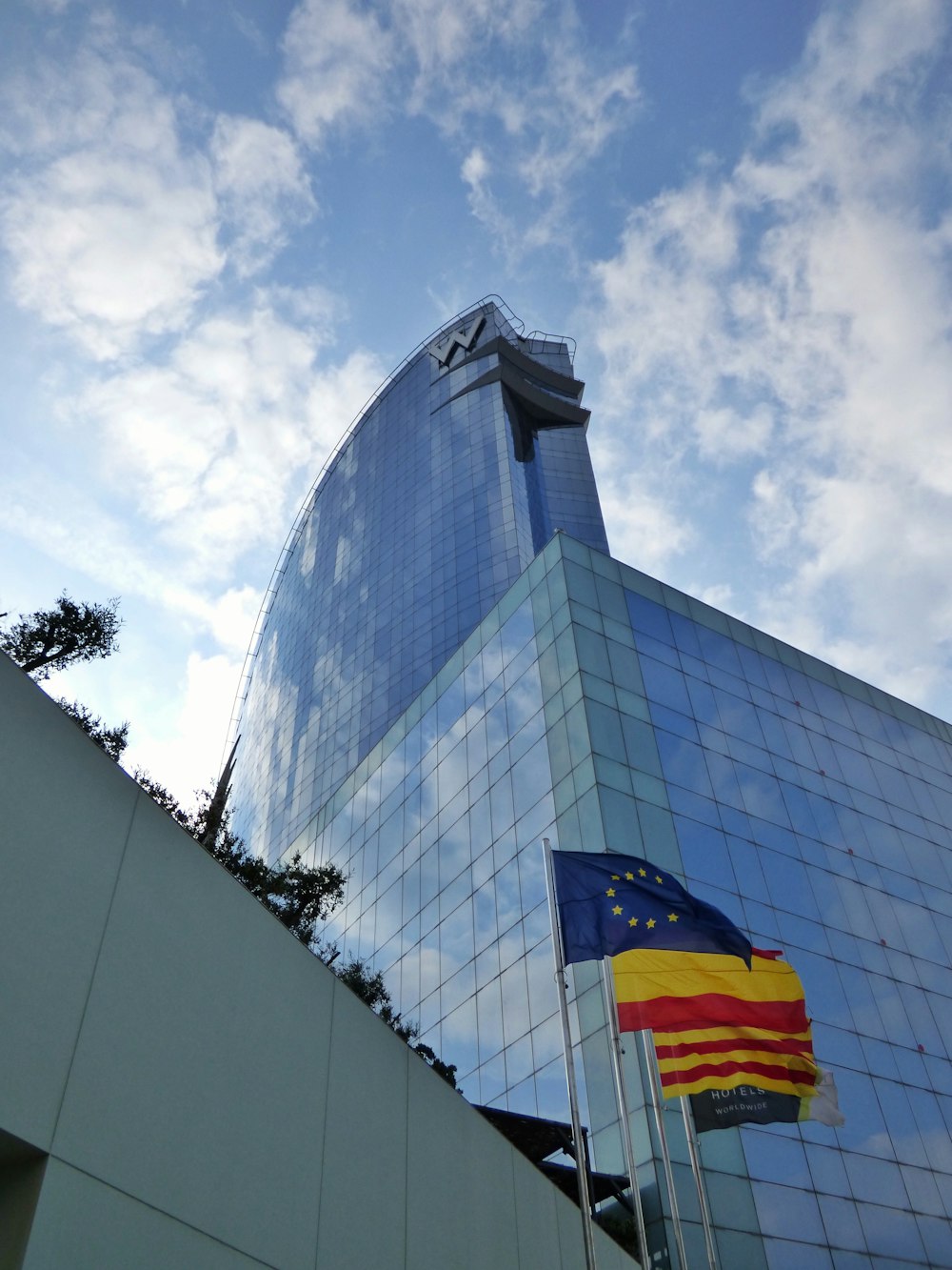 un grand bâtiment en verre avec un drapeau flottant devant lui