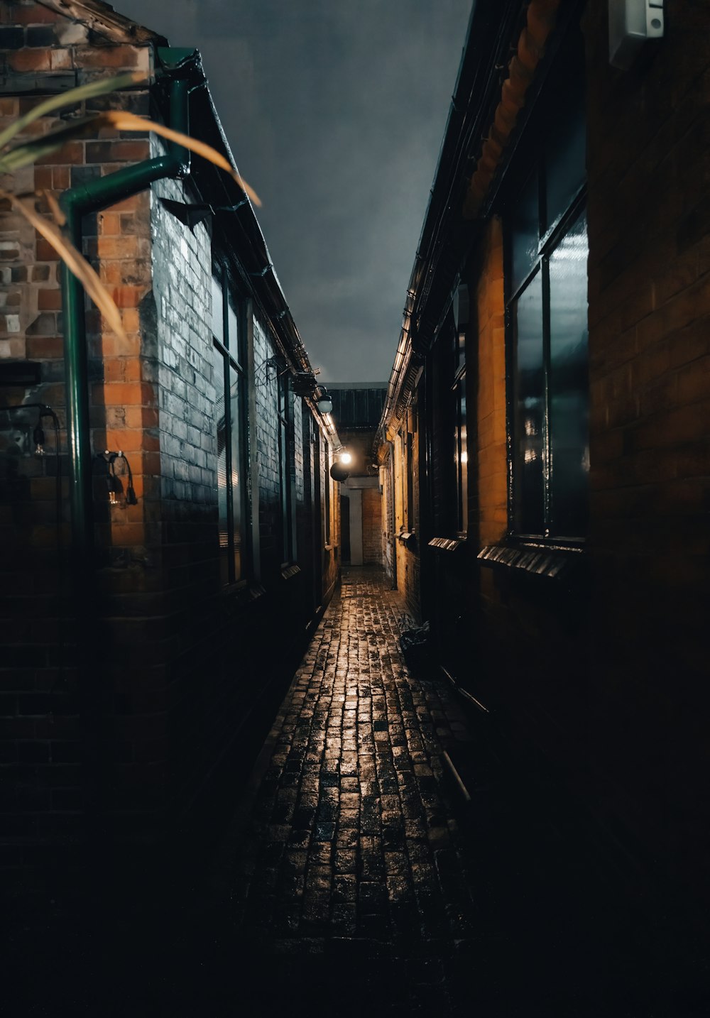 a dark alley way with a brick wall and windows