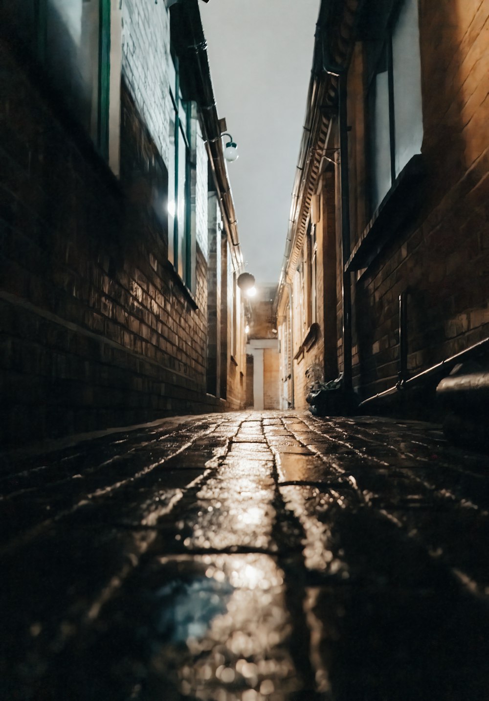 a narrow alley way with a light at the end