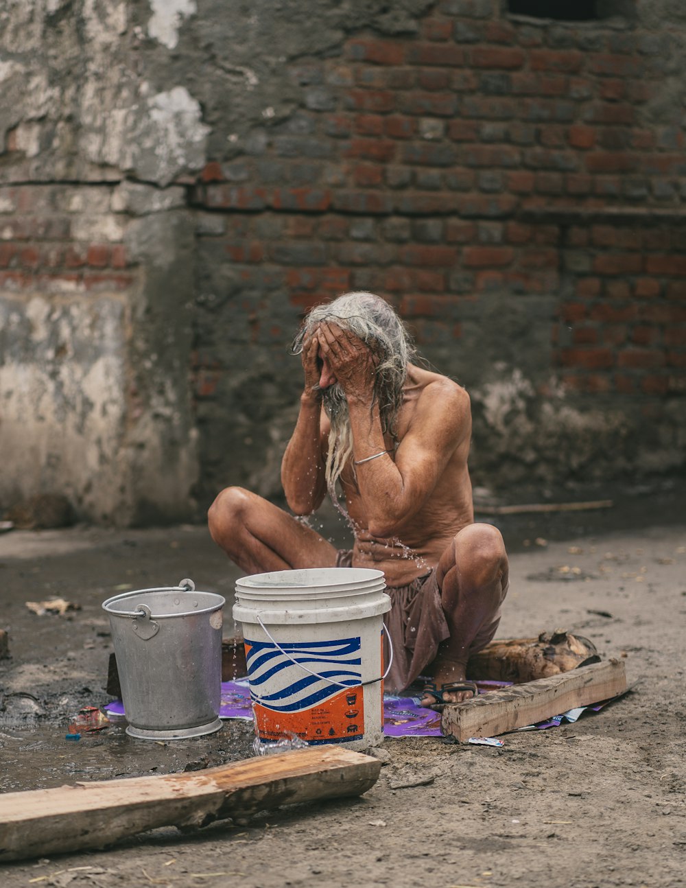 a man sitting on the ground next to a bucket