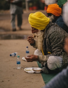 a man with a yellow turban sitting on the ground