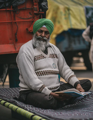 a man with a green turban sitting on a blanket