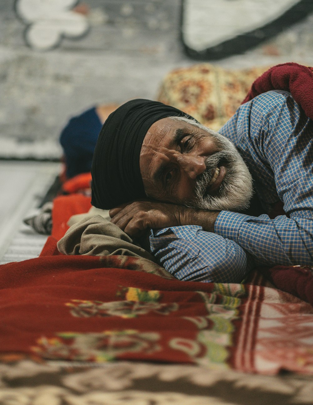 a man laying on top of a bed next to a red blanket