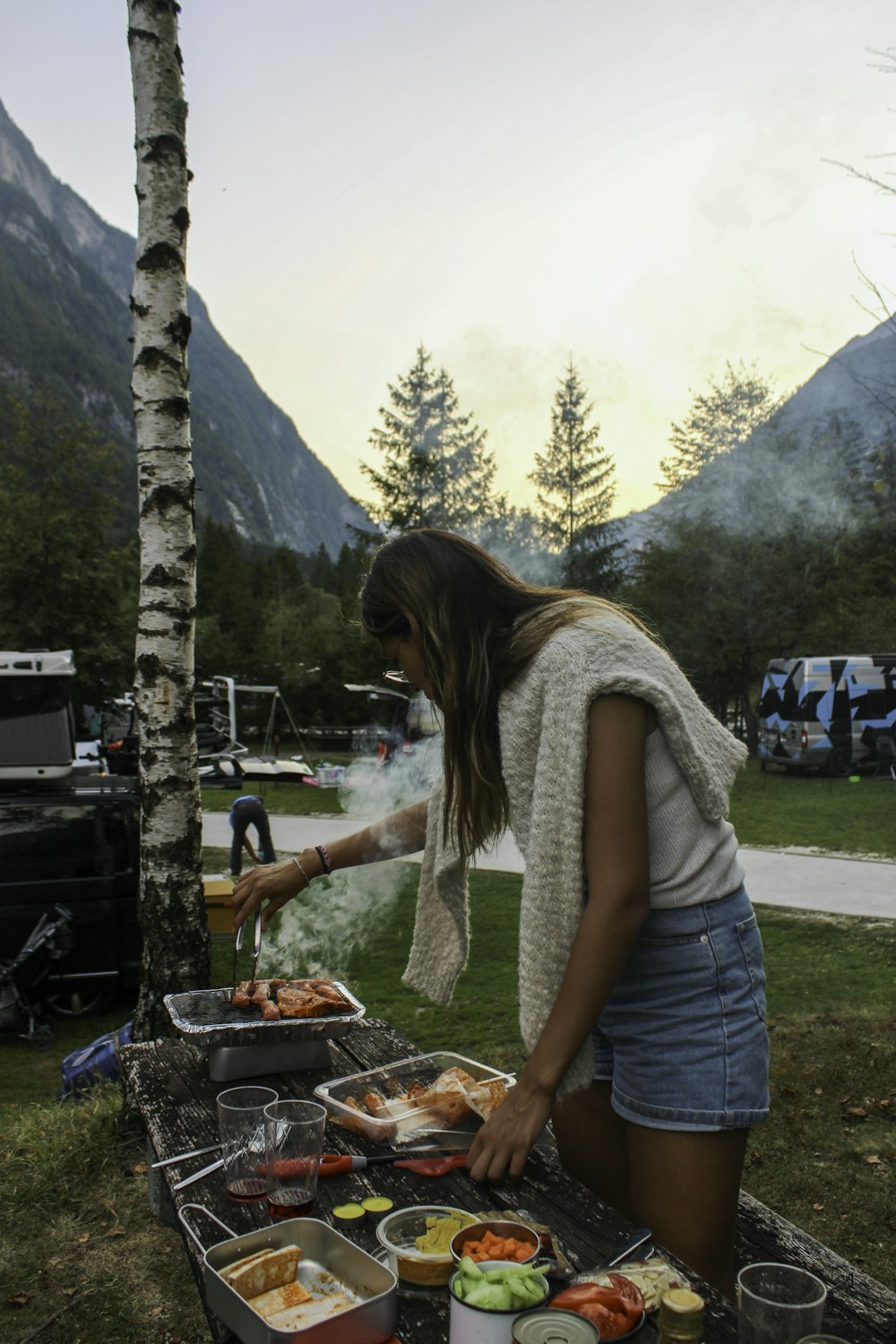 a woman standing over a table filled with food