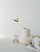 A minimalist ceramic vase with clean lines holding a single wildflower.