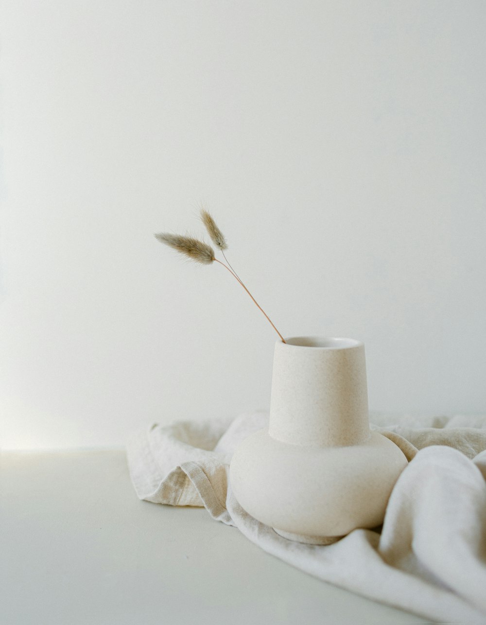 um vaso branco sentado em cima de uma mesa branca
