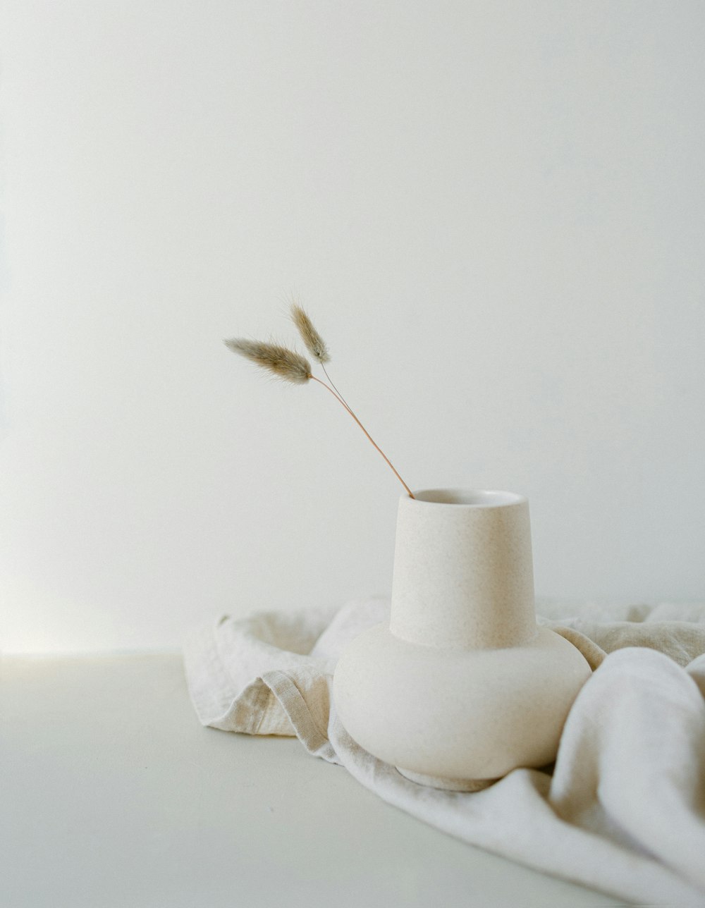 a white vase sitting on top of a white table