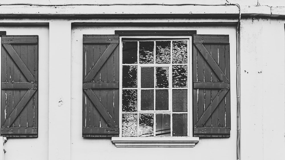 a black and white photo of a window with shutters