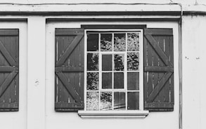 a black and white photo of a window with shutters