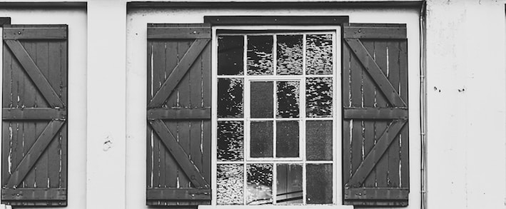 a black and white photo of a window with shutters