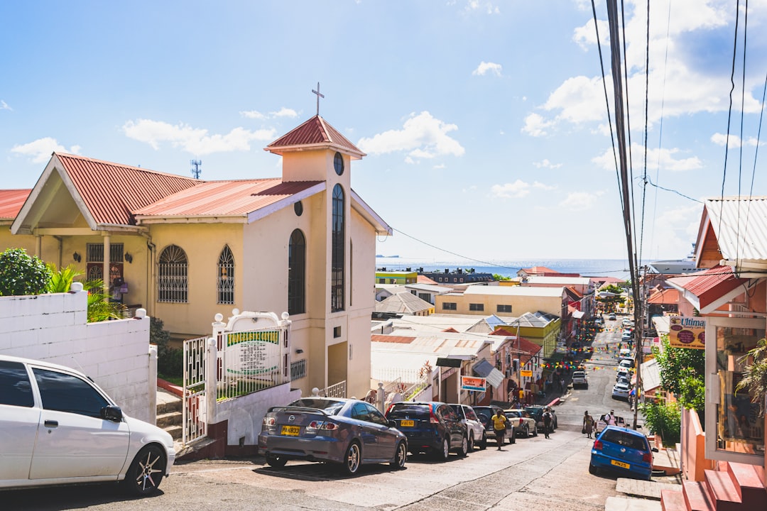 a street with cars parked in front of a church, View from Church looking down a hill towards the sea