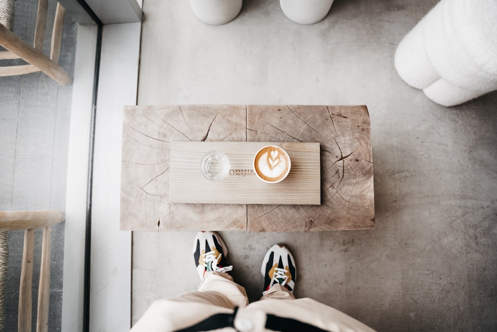 eine Person mit den Füßen auf einem Tisch mit einer Tasse Kaffee