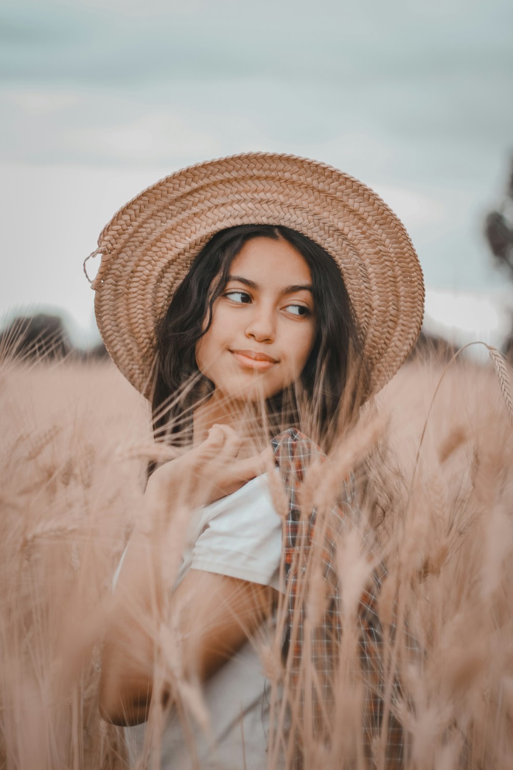 a woman wearing a straw hat standing in a field