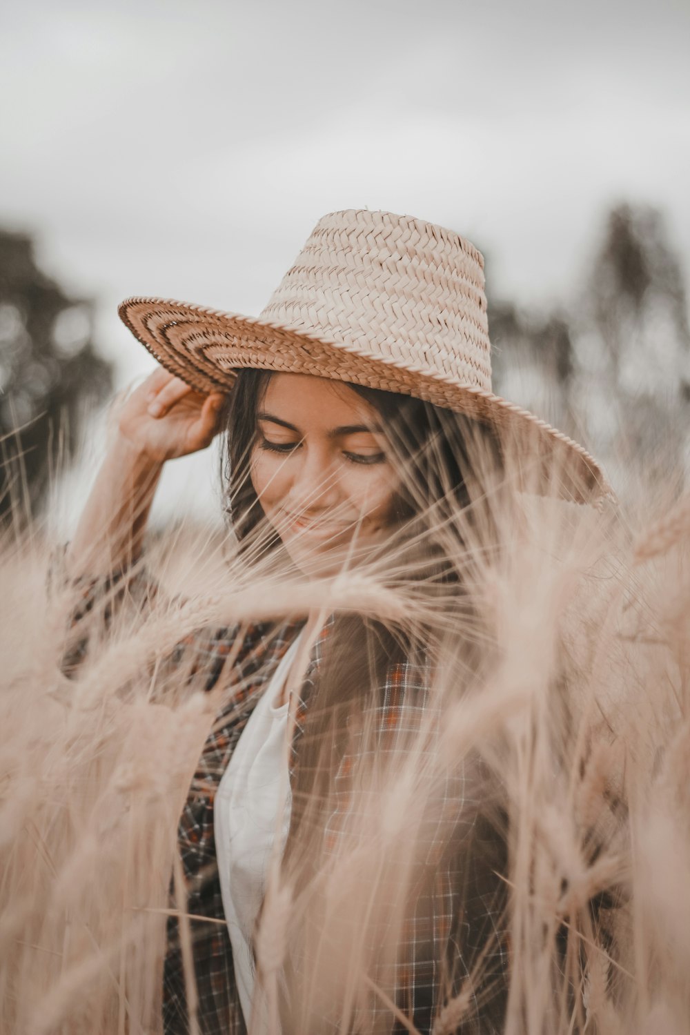 a woman in a straw hat standing in a field