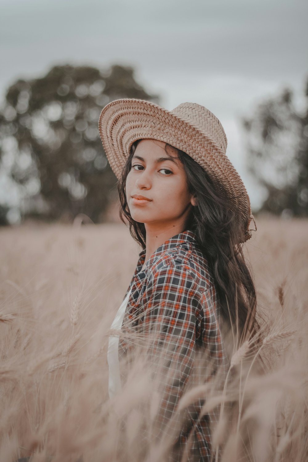 a woman wearing a hat standing in a field