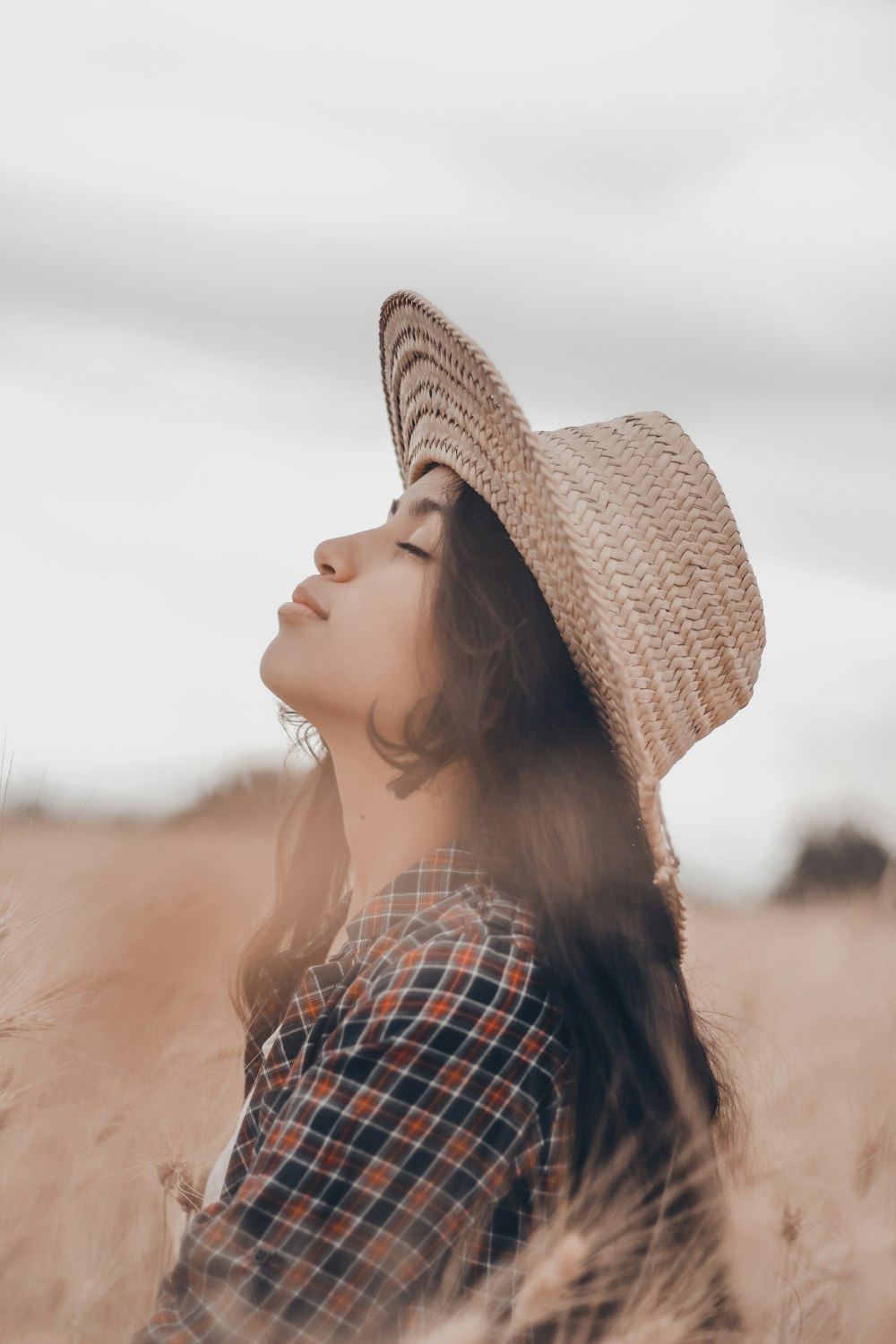 a woman wearing a hat standing in a field