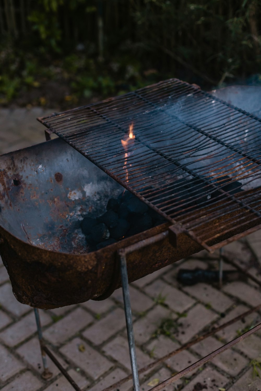 a bbq grill on a brick patio with a lit flame