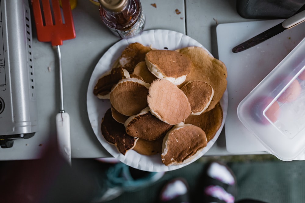 une assiette blanche garnie de crêpes à côté d’un couteau et d’une fourchette