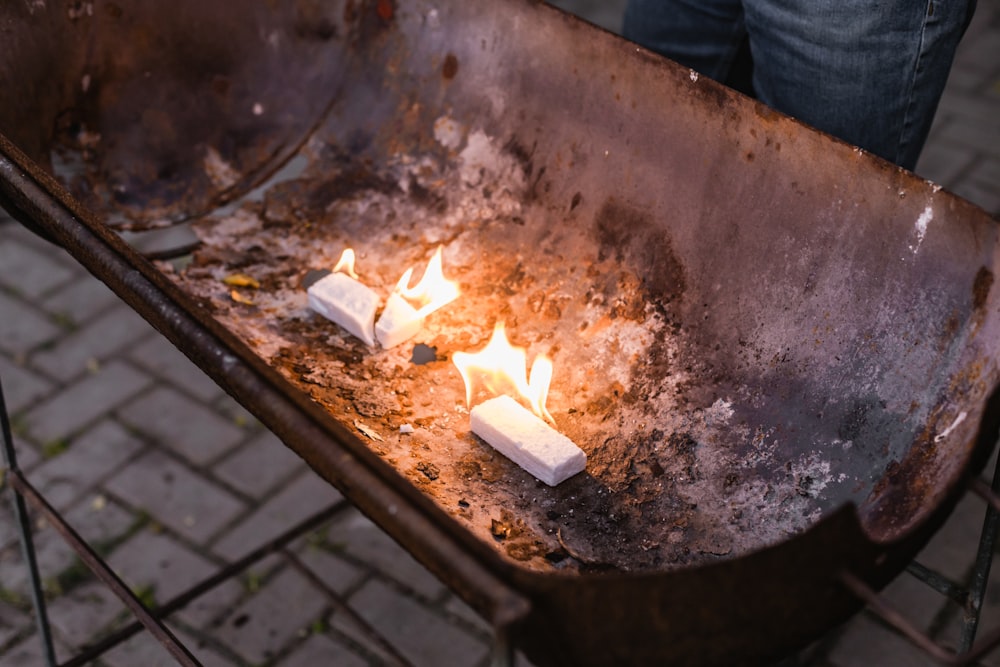 a person holding a metal tray filled with lit candles