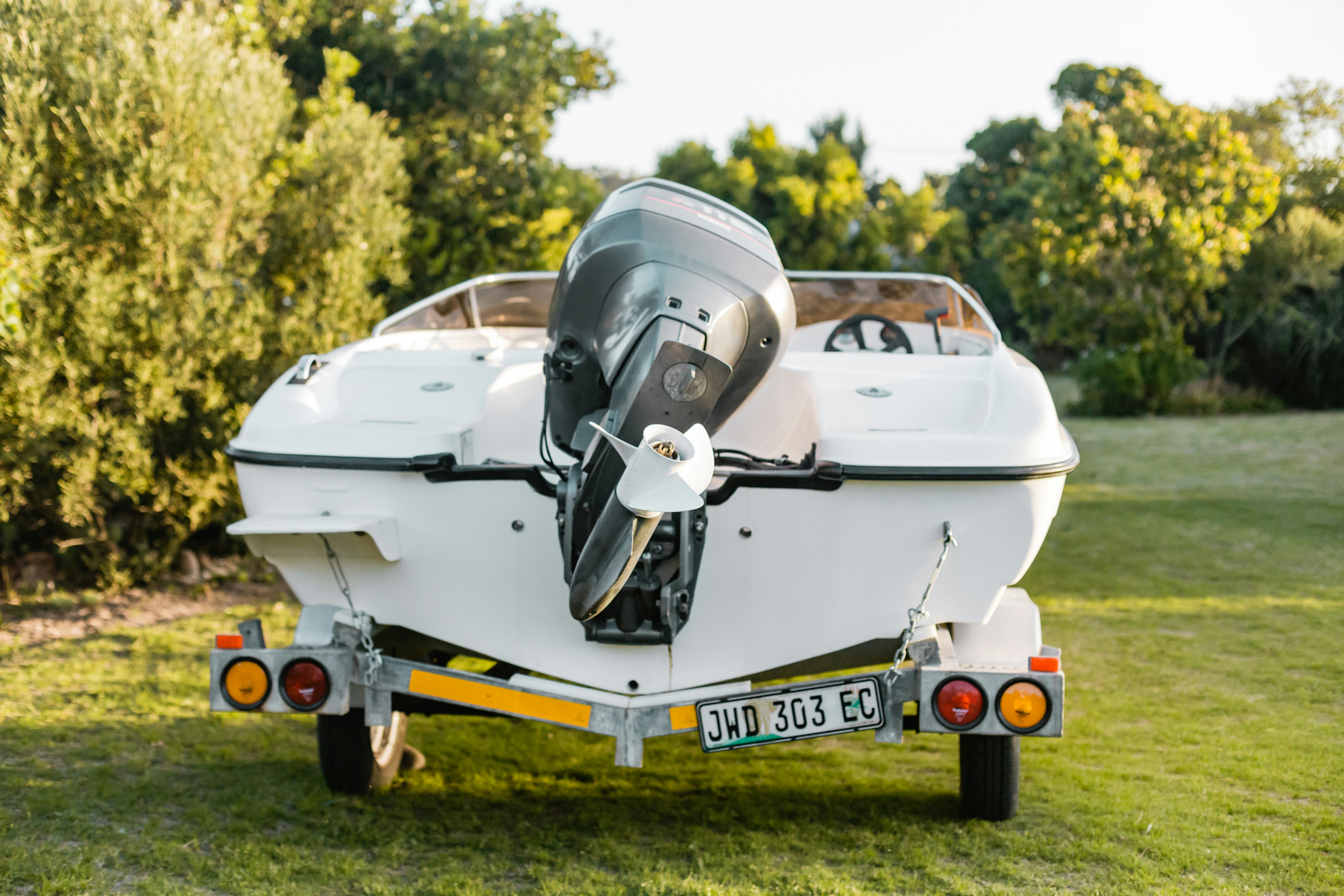 a white boat sitting on top of a lush green field