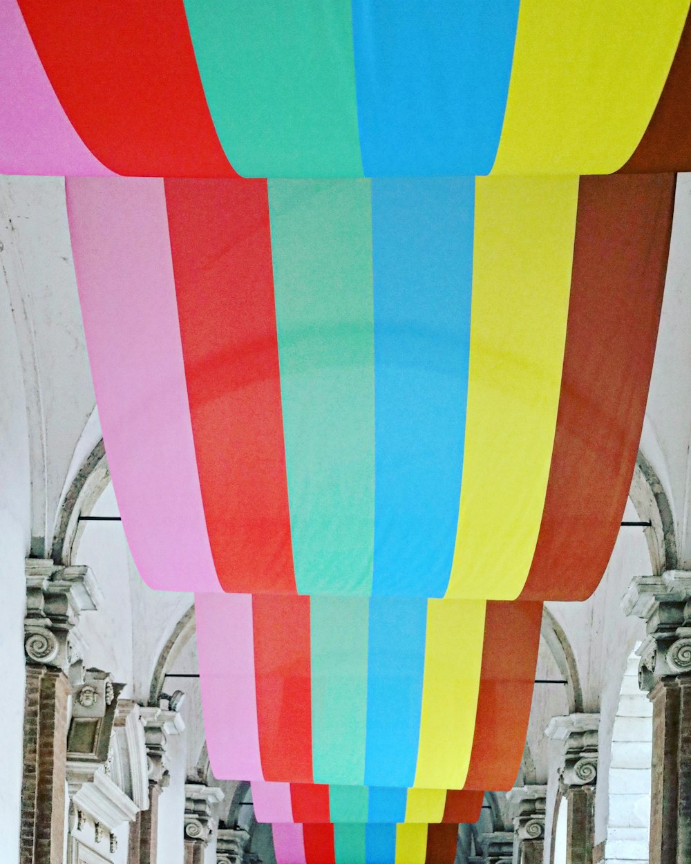 a group of people standing under a rainbow colored umbrella