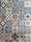 A collection of intricately designed ceramic tiles with various geometric and floral patterns. Each tile features unique motifs with combinations of blue, beige, and terracotta colors. The patterns range from symmetrical star shapes to more organic floral designs, providing a vintage and artistic appearance.