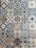 A collection of intricately designed ceramic tiles with various geometric and floral patterns. Each tile features unique motifs with combinations of blue, beige, and terracotta colors. The patterns range from symmetrical star shapes to more organic floral designs, providing a vintage and artistic appearance.