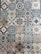 A collection of intricately designed ceramic tiles with various geometric and floral patterns. Each tile features unique motifs with combinations of blue, beige, and terracotta colors. The patterns range from symmetrical star shapes to more organic floral designs, providing a vintage and artistic appearance.