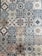 A collection of intricately designed ceramic tiles with various geometric and floral patterns. Each tile features unique motifs with combinations of blue, beige, and terracotta colors. The patterns range from symmetrical star shapes to more organic floral designs, providing a vintage and artistic appearance.