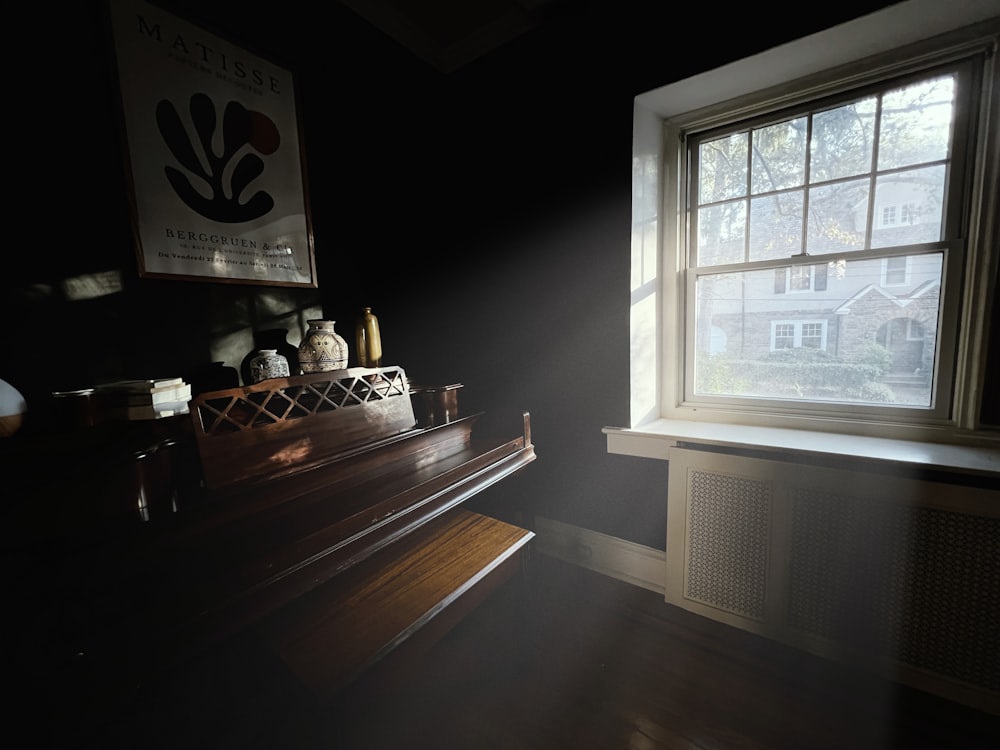 a piano in a dark room next to a window
