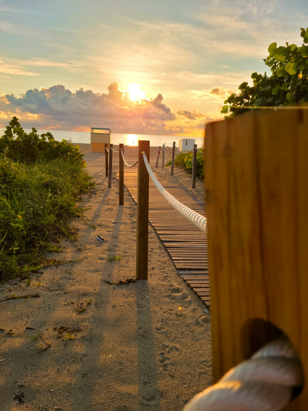 a wooden walkway leading to the beach at sunset