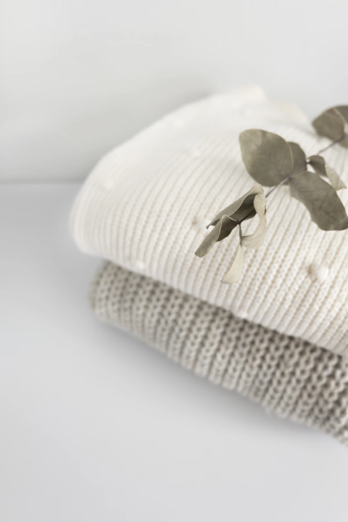 Editorial photography of a baby's hand on a soft neutral blanket.
