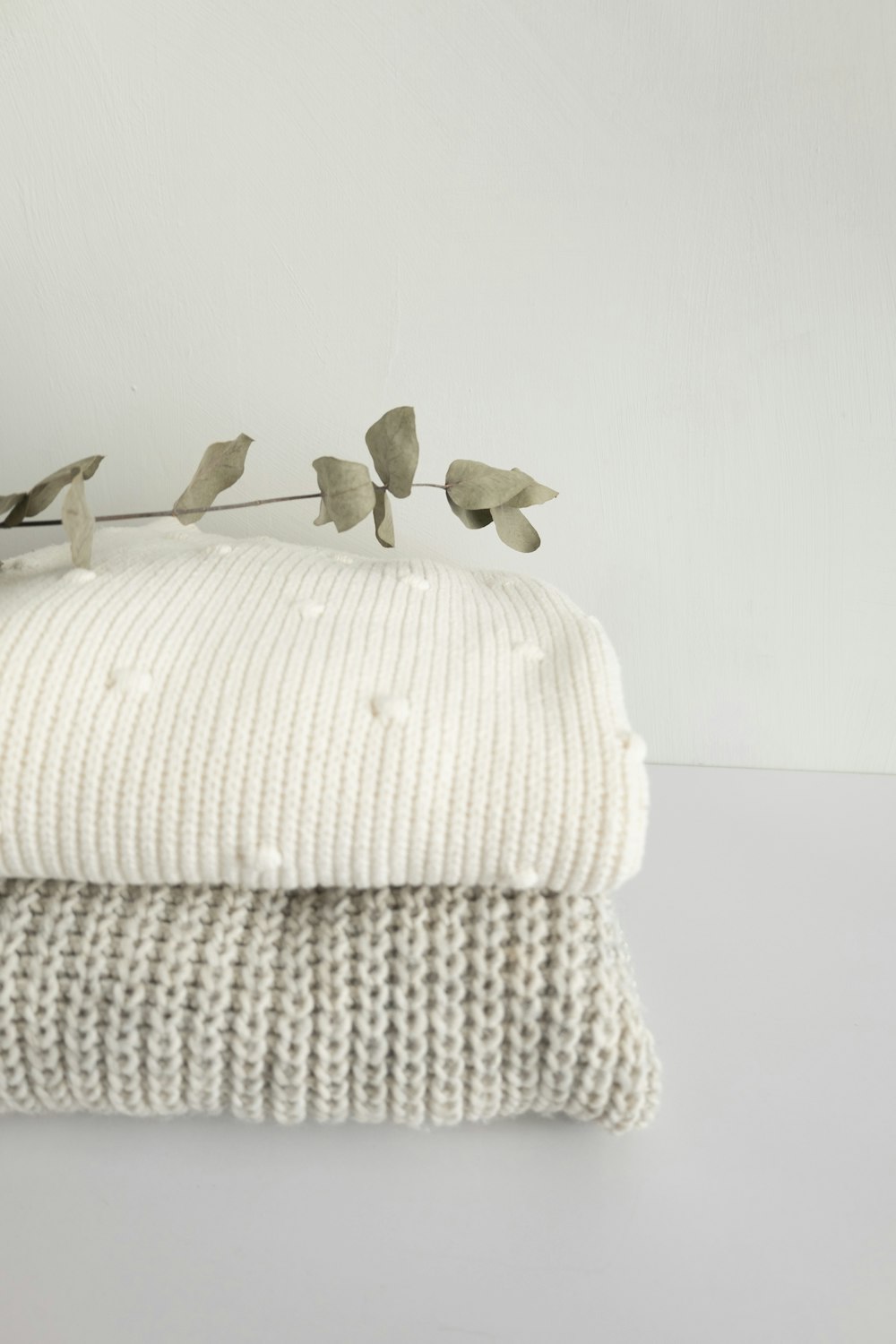 a stack of folded blankets with a plant on top