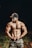 a shirtless man standing in a field with his hands on his hips