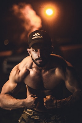 a shirtless man with a baseball cap on