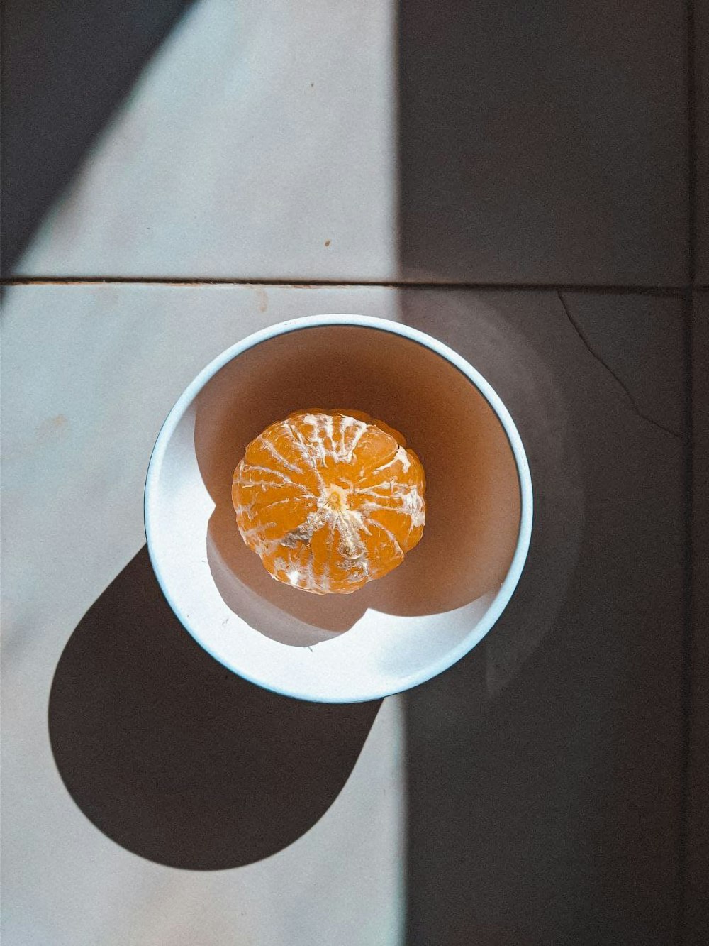 an orange sitting in a white bowl on a table