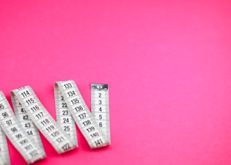 a group of measuring tape sitting on top of a pink surface