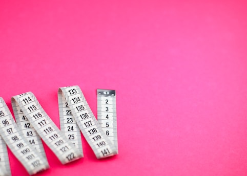 a group of measuring tape sitting on top of a pink surface