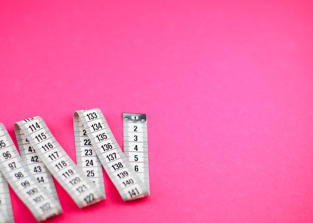 a group of measuring tape sitting on top of a pink surface