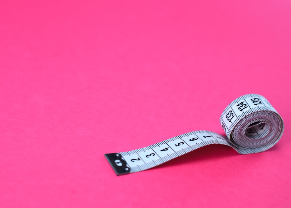 a measuring tape on a pink background