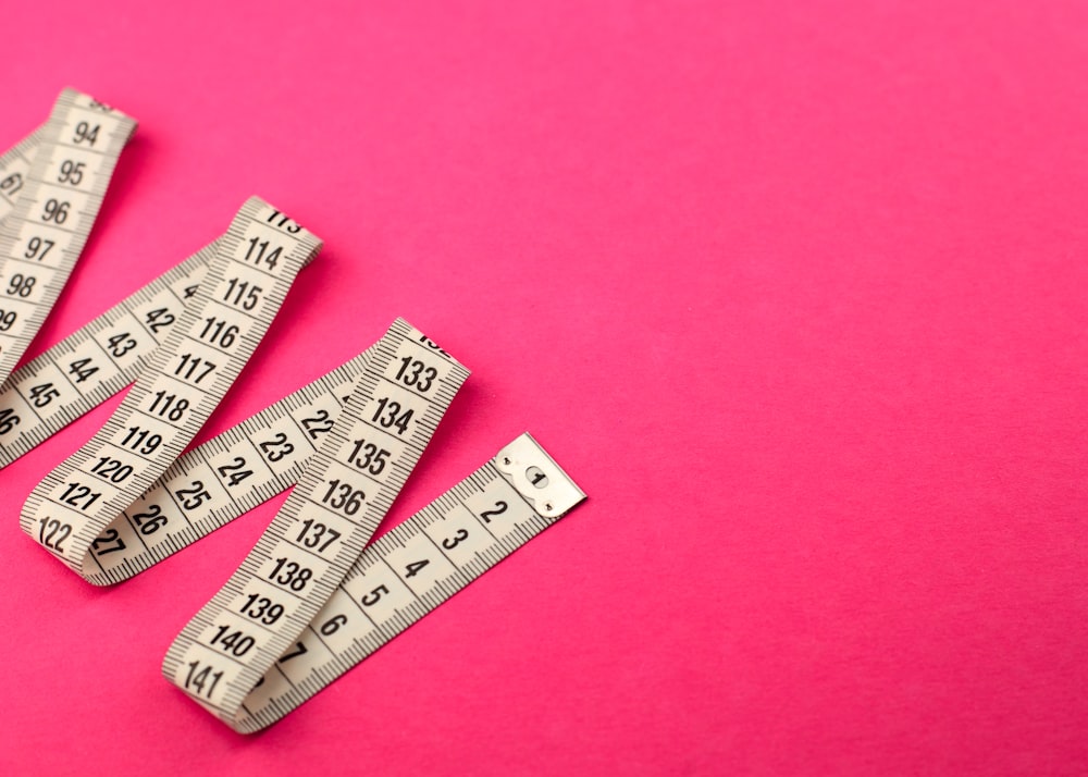 a group of measuring tape sitting on top of a pink surface