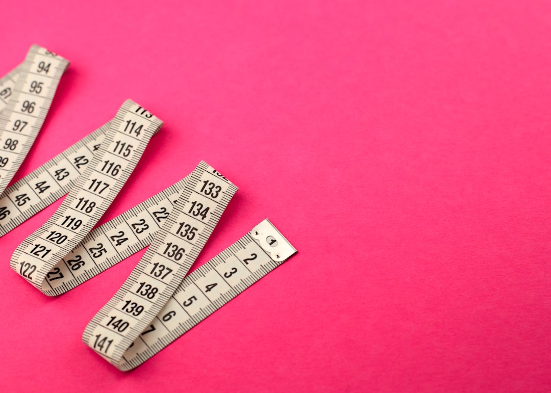 a group of measuring tape sitting on top of a pink surface,