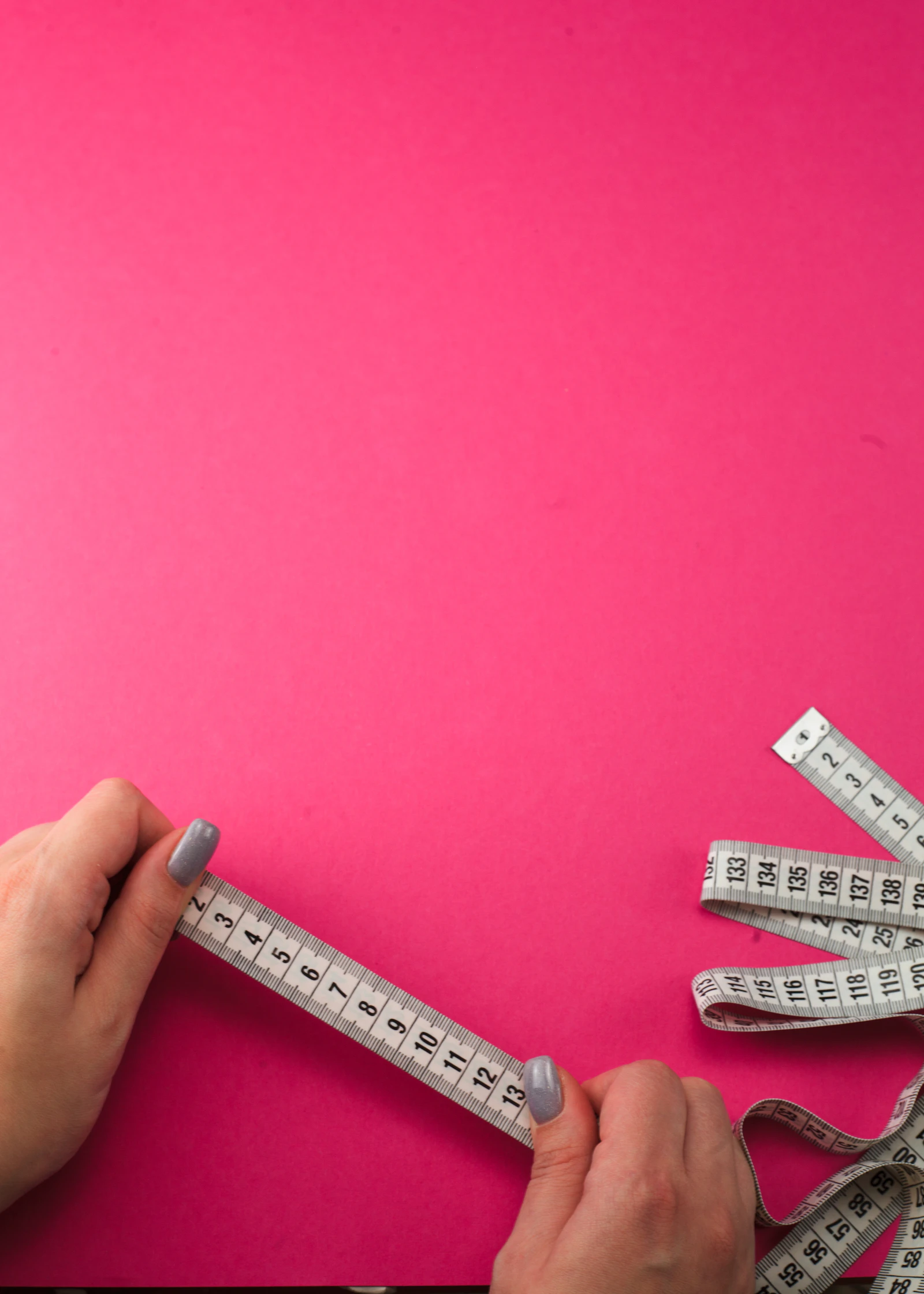 A soft measuring tape being held between two fingers